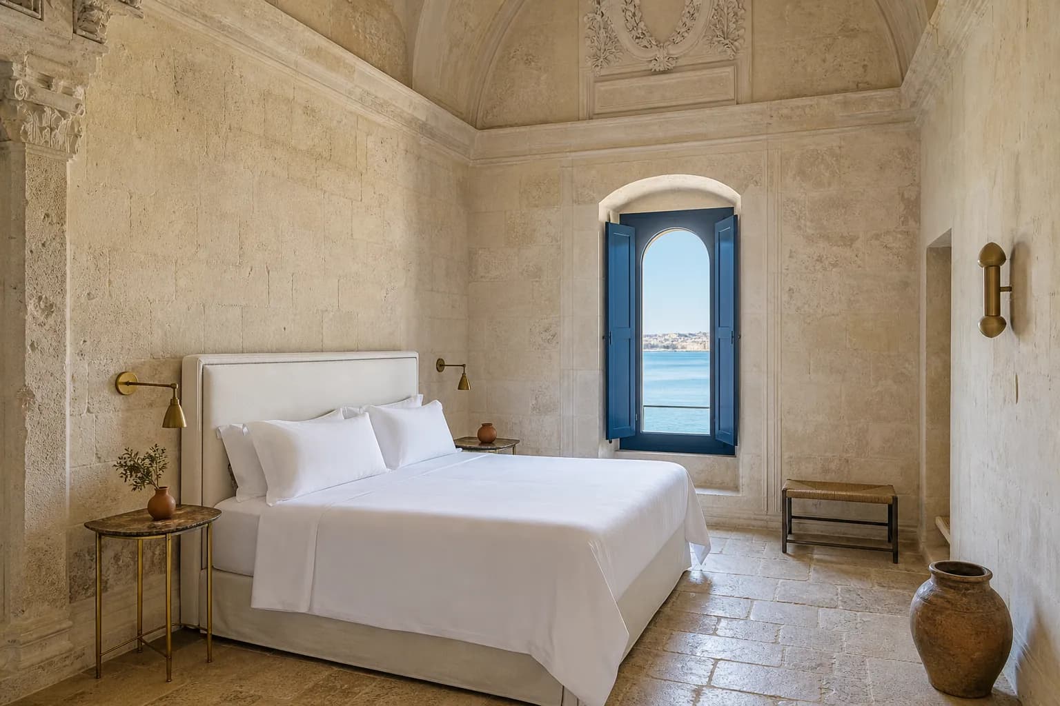 A Camera del Mare in late morning: white linen, a stone floor, the blue shutters half closed against the sun